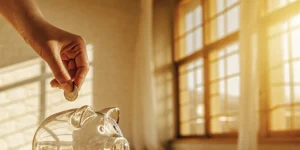 A hand saving a coin in a piggy bank to buy down an interest rate.