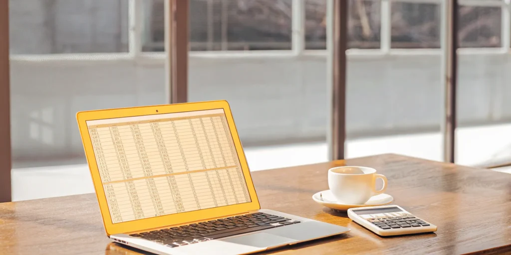 Laptop displaying a commercial DSCR calculator next to a physical calculator.