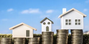 A model house on a stack of coins from a mortgage lender that pays closing costs.