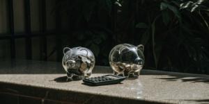 A calculator and two piggy banks comparing the savings of a permanent vs temporary buydown.